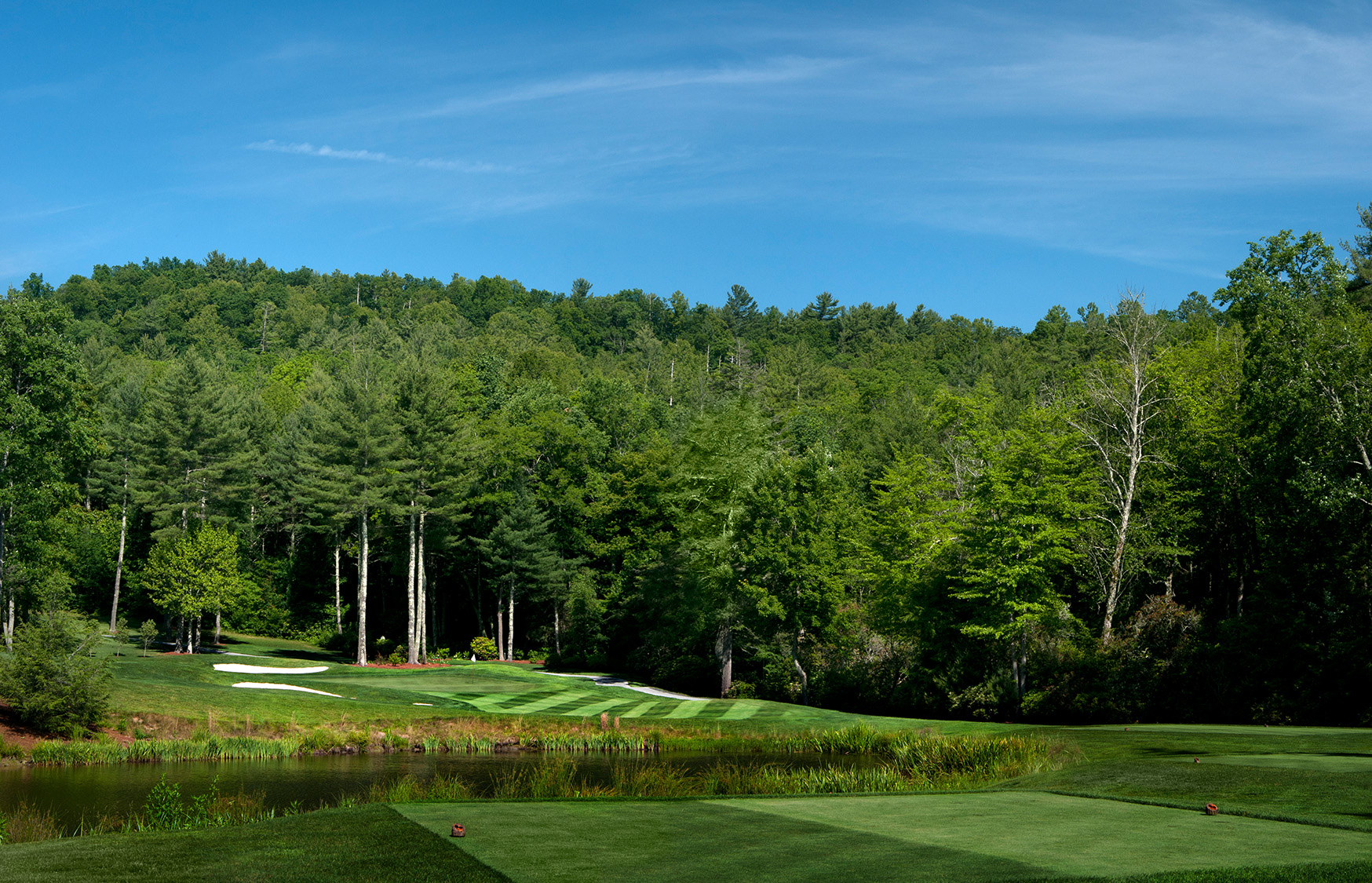 a golf course with trees and a blue sky