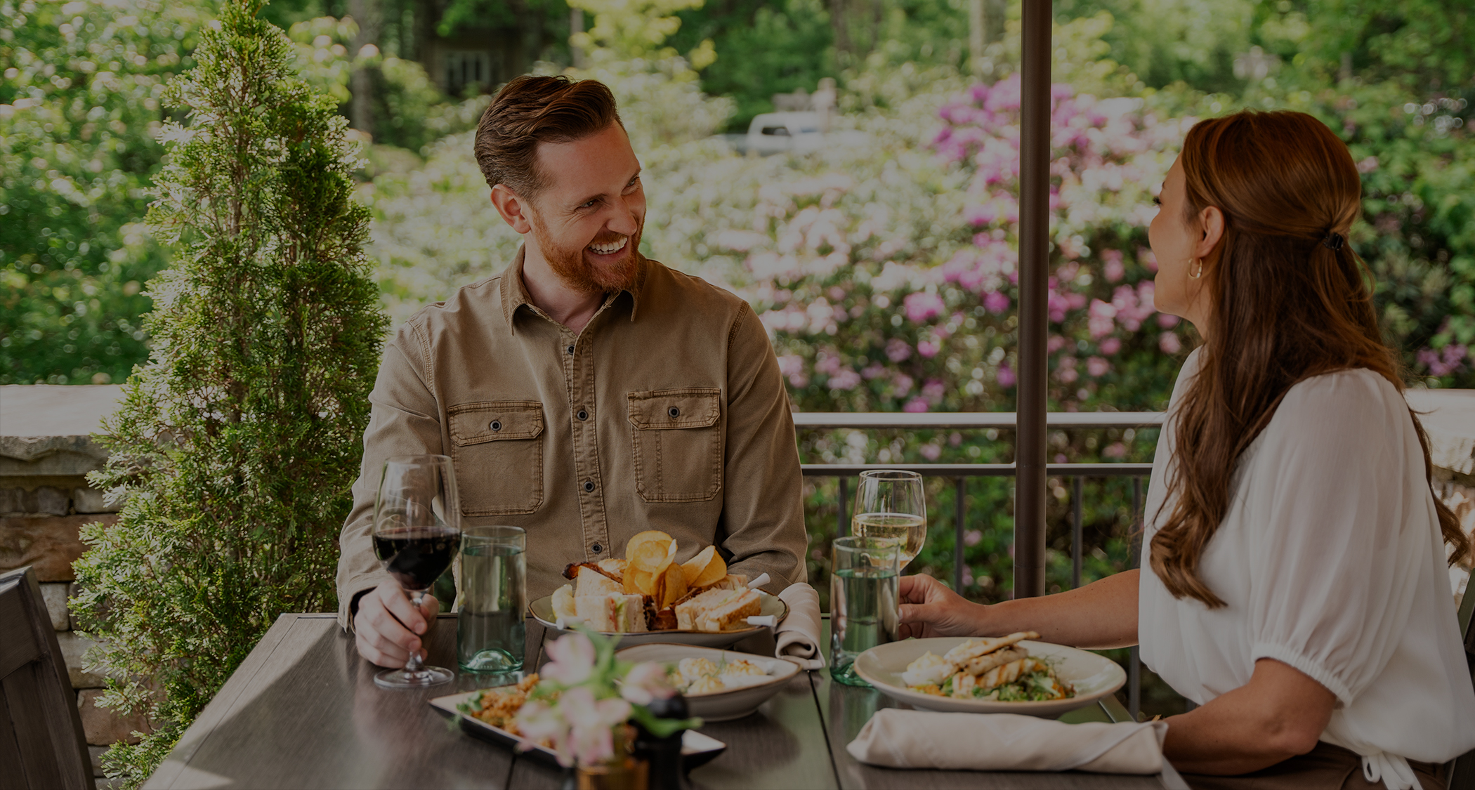 a man and woman sitting at a table with food and drinks