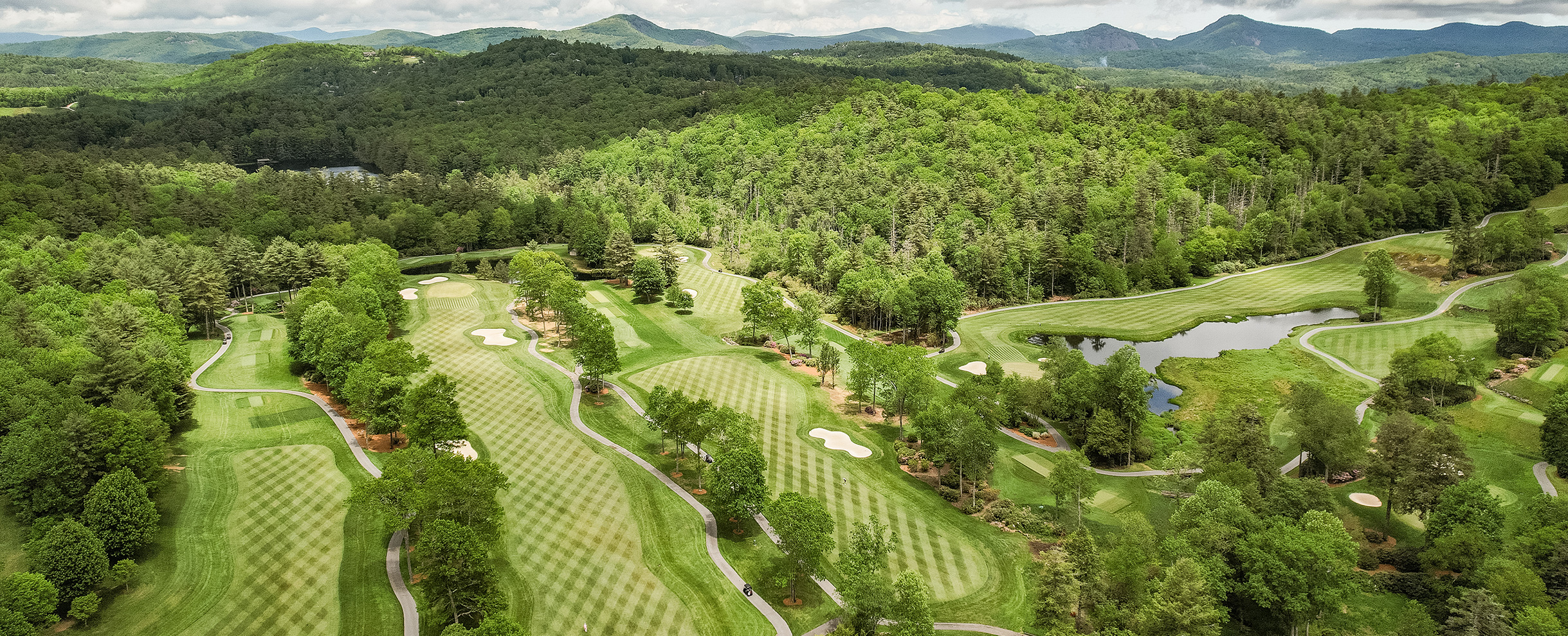 a golf course with trees and mountains in the background