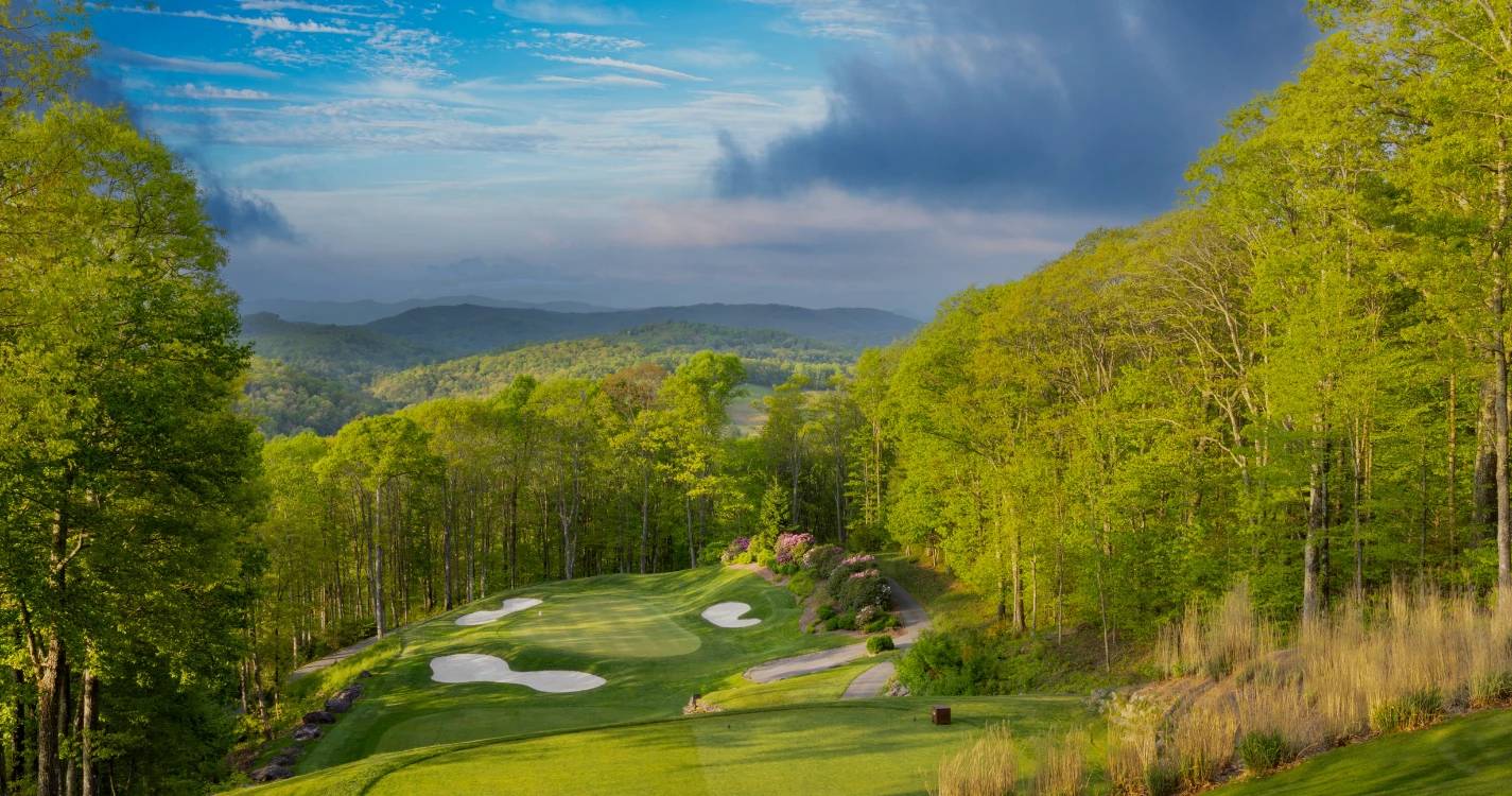 a golf course with trees and blue sky