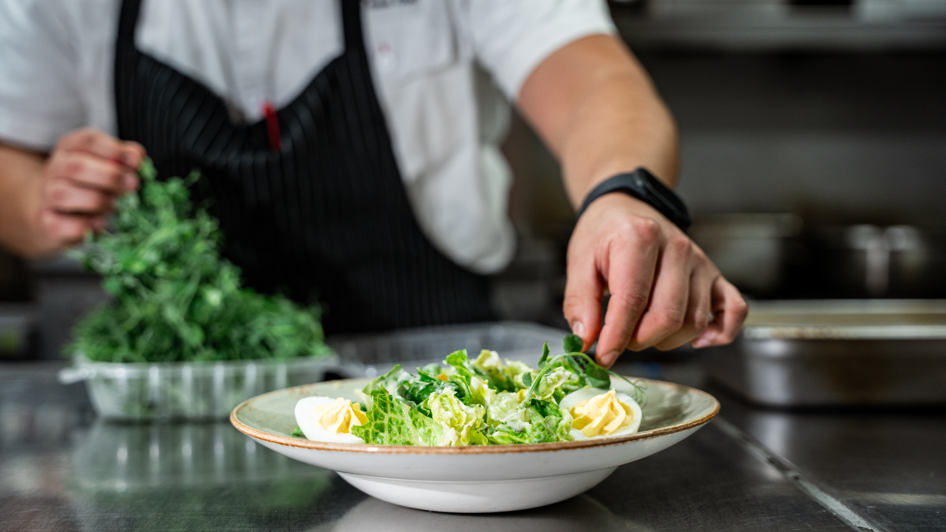 a person putting egg on a salad
