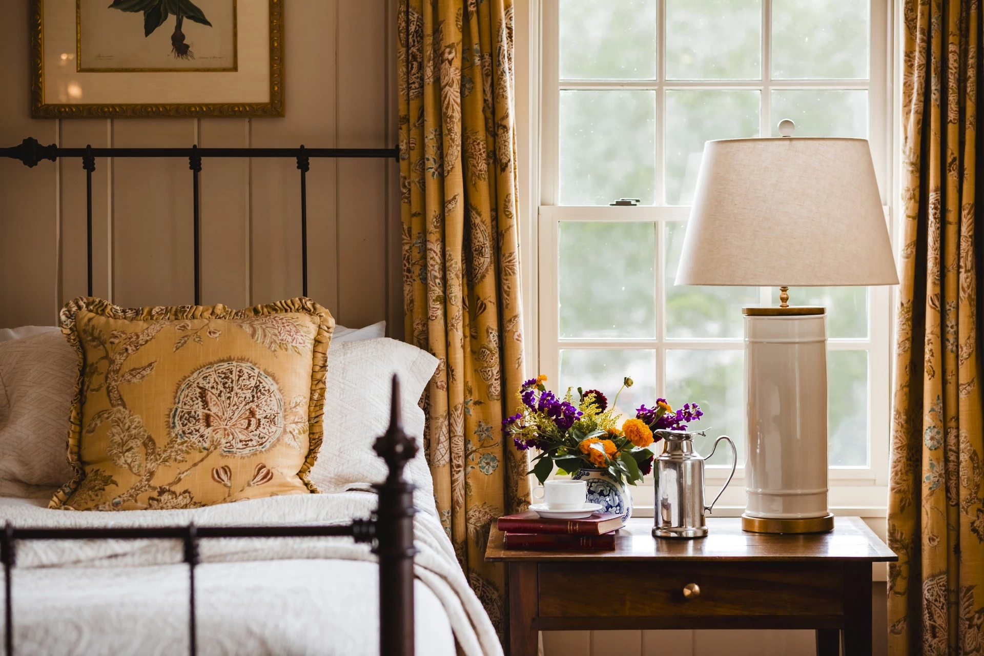 a bed with a lamp and flowers on a table