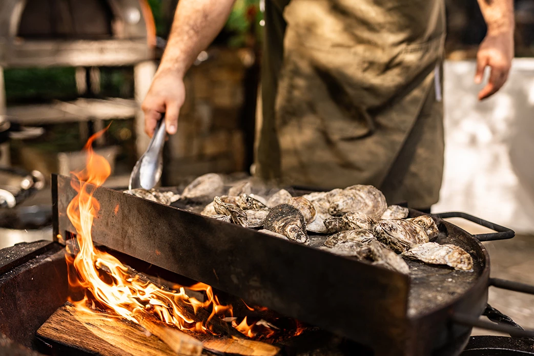 a man cooking oysters on a grill