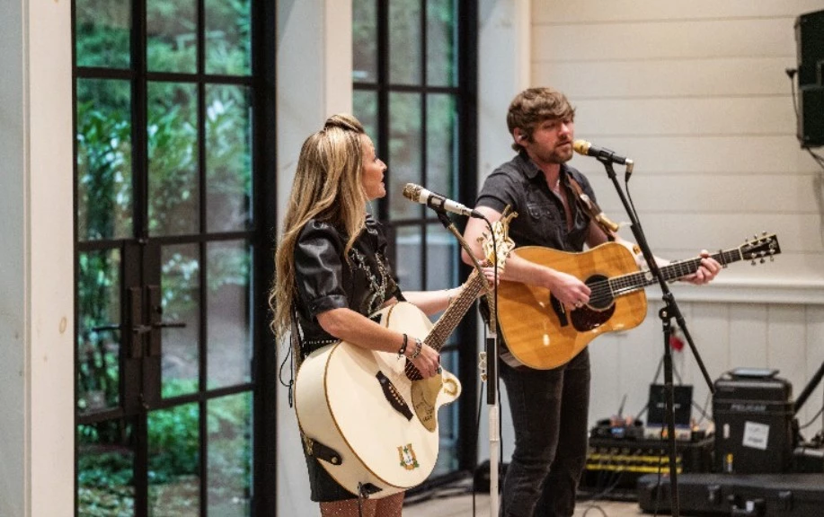 a man and woman playing guitars and singing
