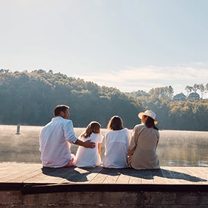 a group of people sitting on a dock overlooking a body of water