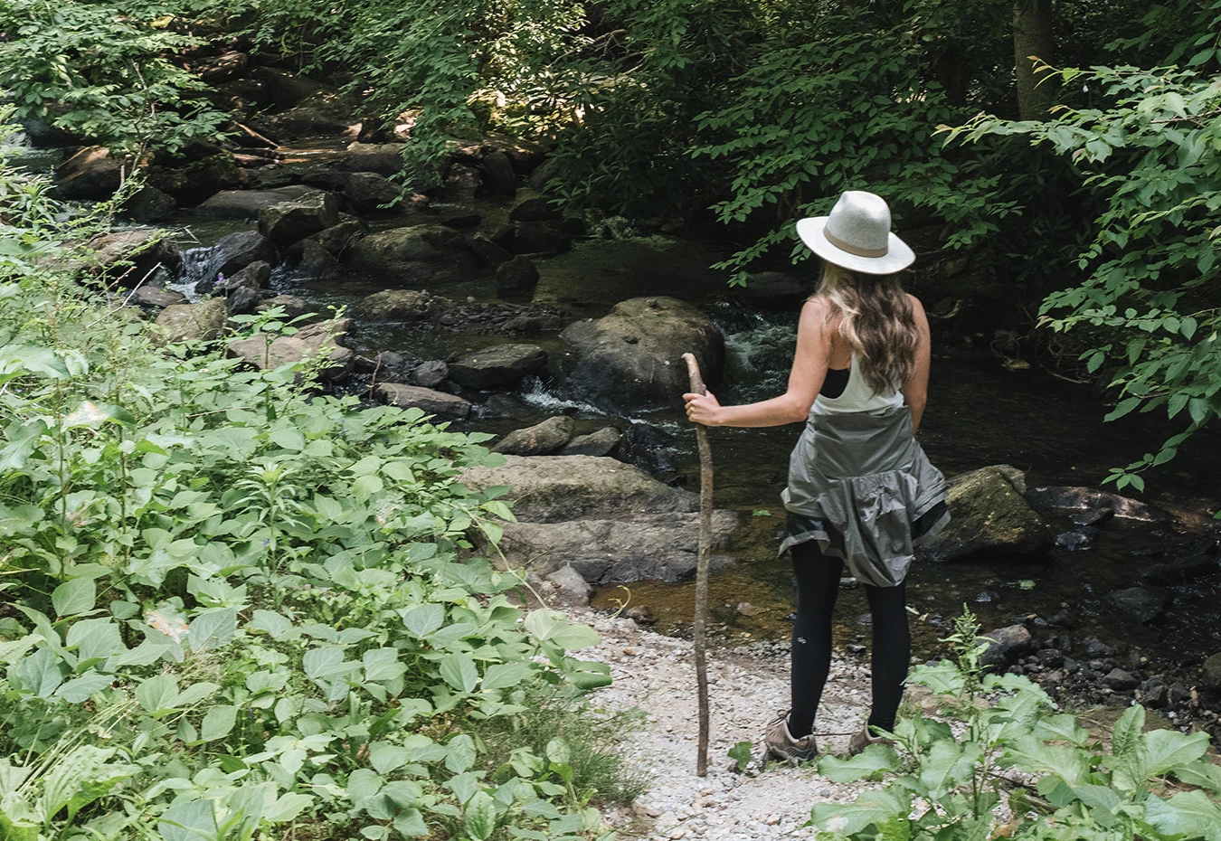 a woman standing on a path with a stick