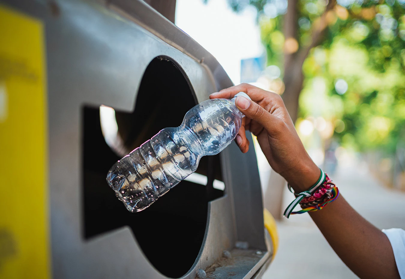 a hand holding a plastic bottle in a trash can