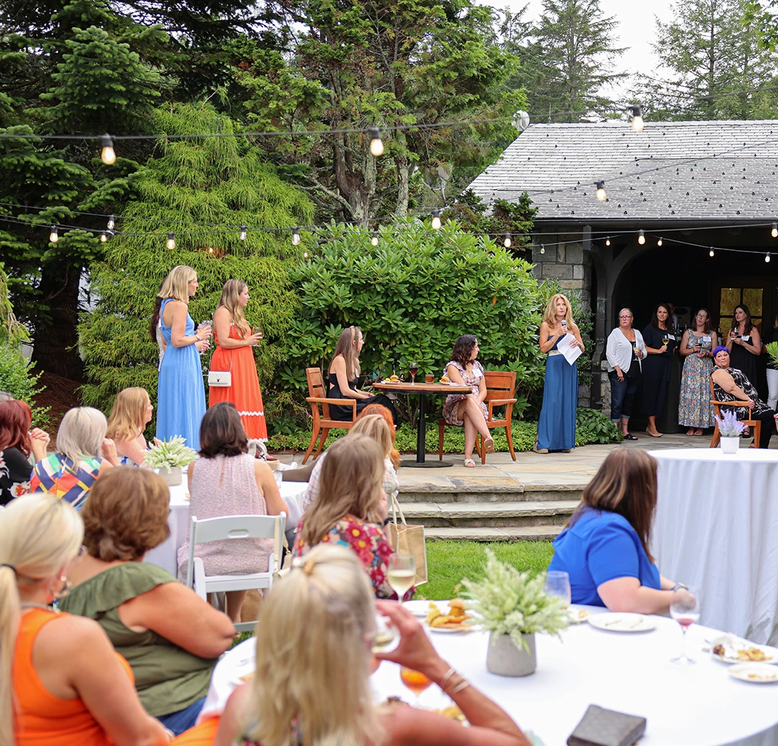 a group of women in orange dresses on a patio with a group of people