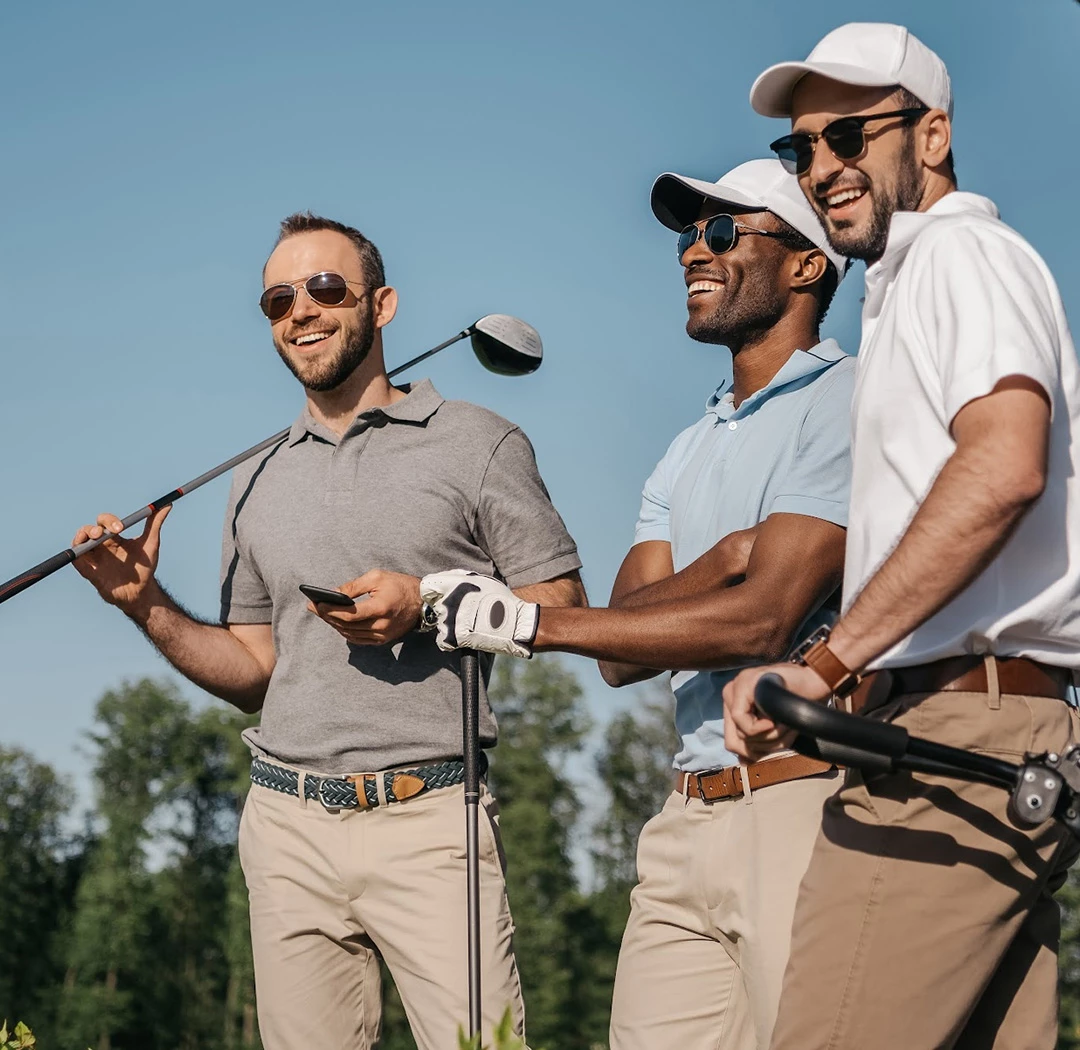 a group of men holding golf clubs and standing on a golf course