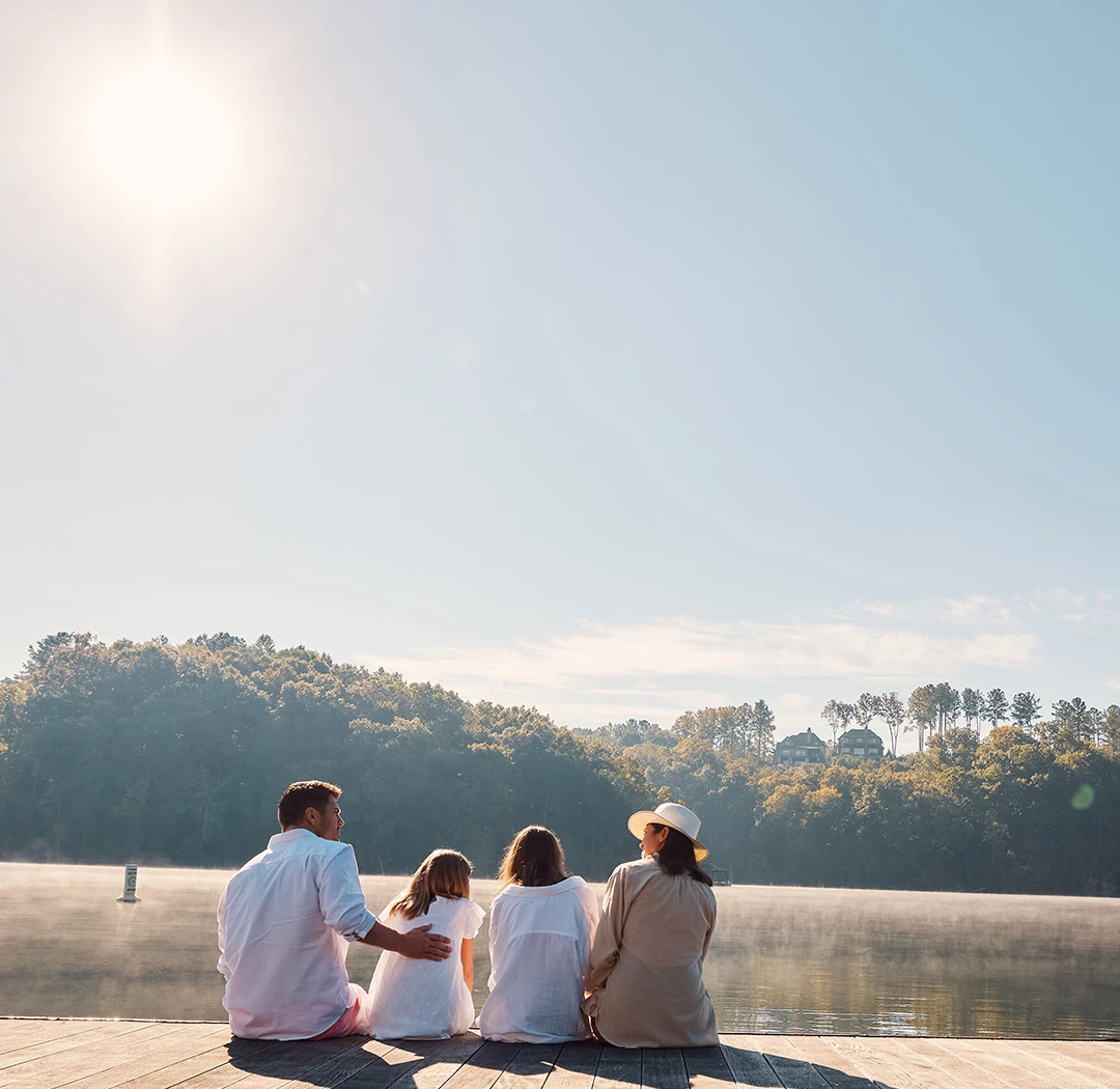 a group of people sitting on a dock by a lake