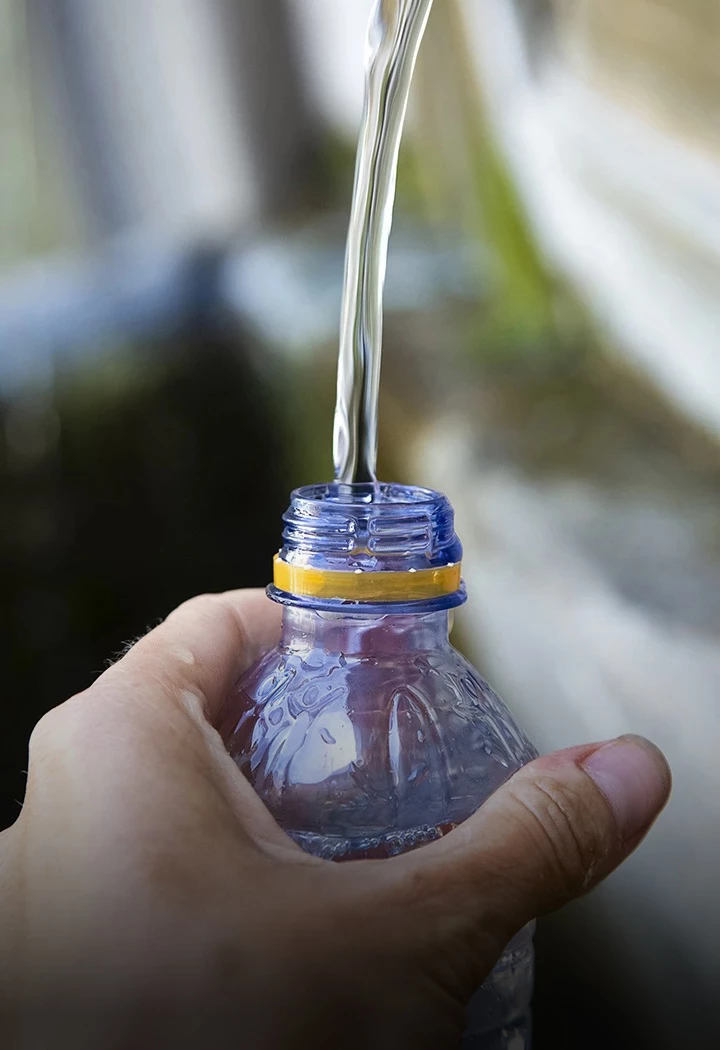 a person pouring water into a small bottle