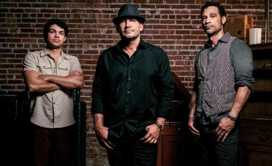 a group of men standing in front of a brick wall
