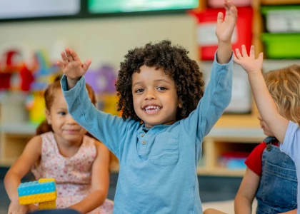 a child raising their hands in a classroom
