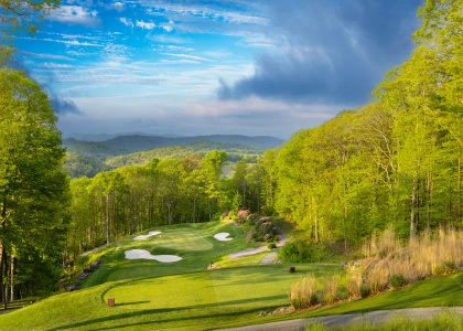 a golf course with trees and blue sky