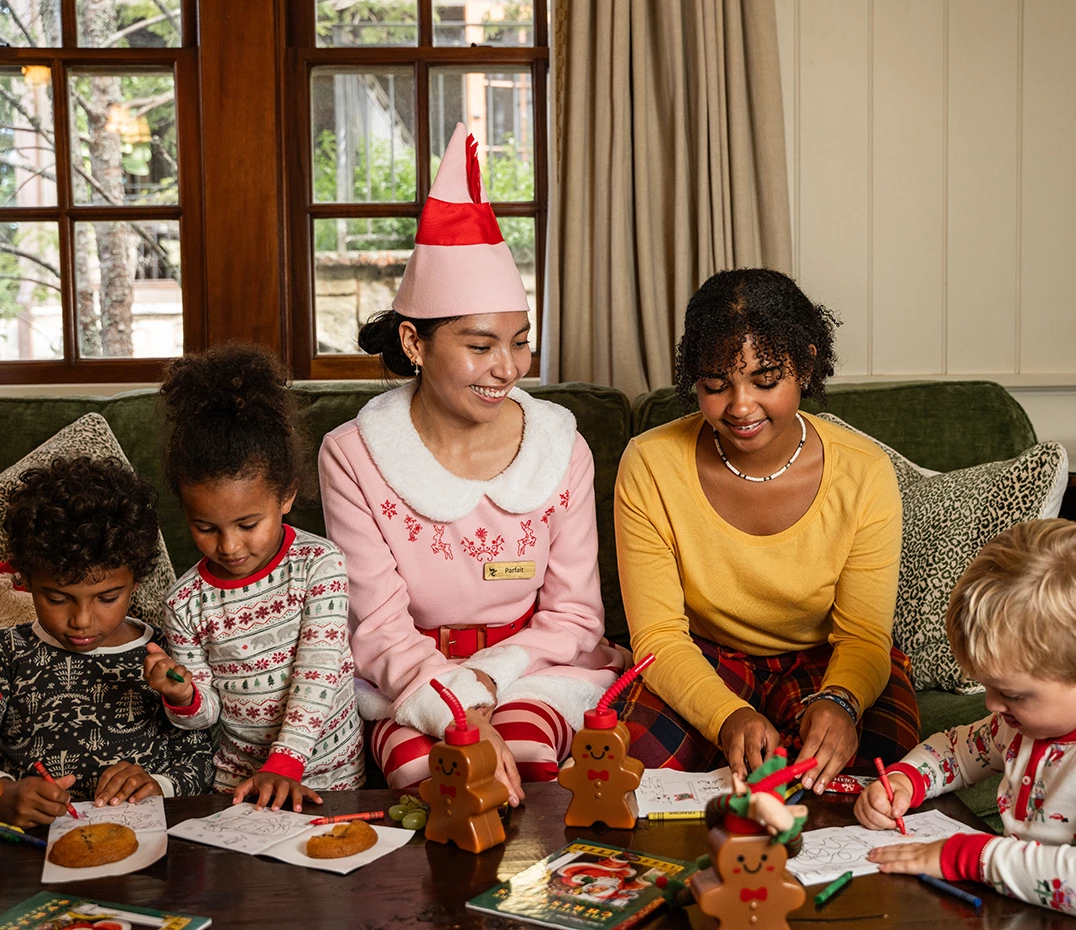 a group of people sitting around a table with a table full of cookies