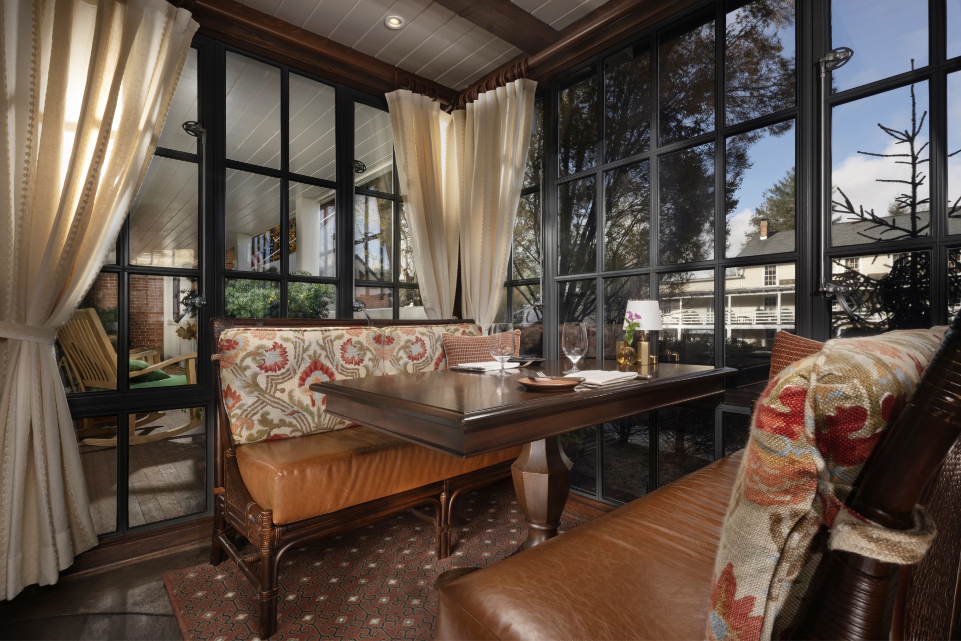 a table with a brown cushion and a brown couch in a room with windows