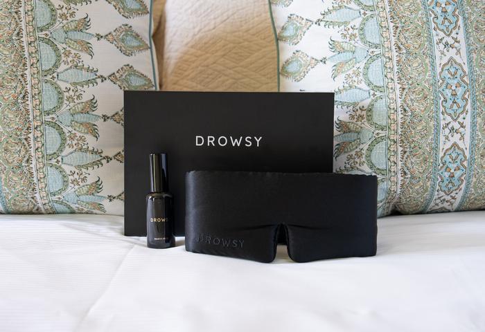 a black eye mask and a bottle of nail polish on a bed