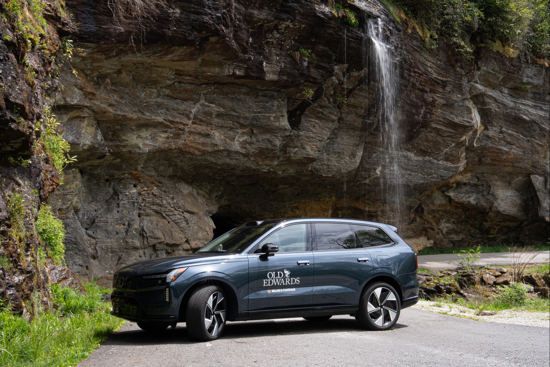 a car parked on a road next to a waterfall