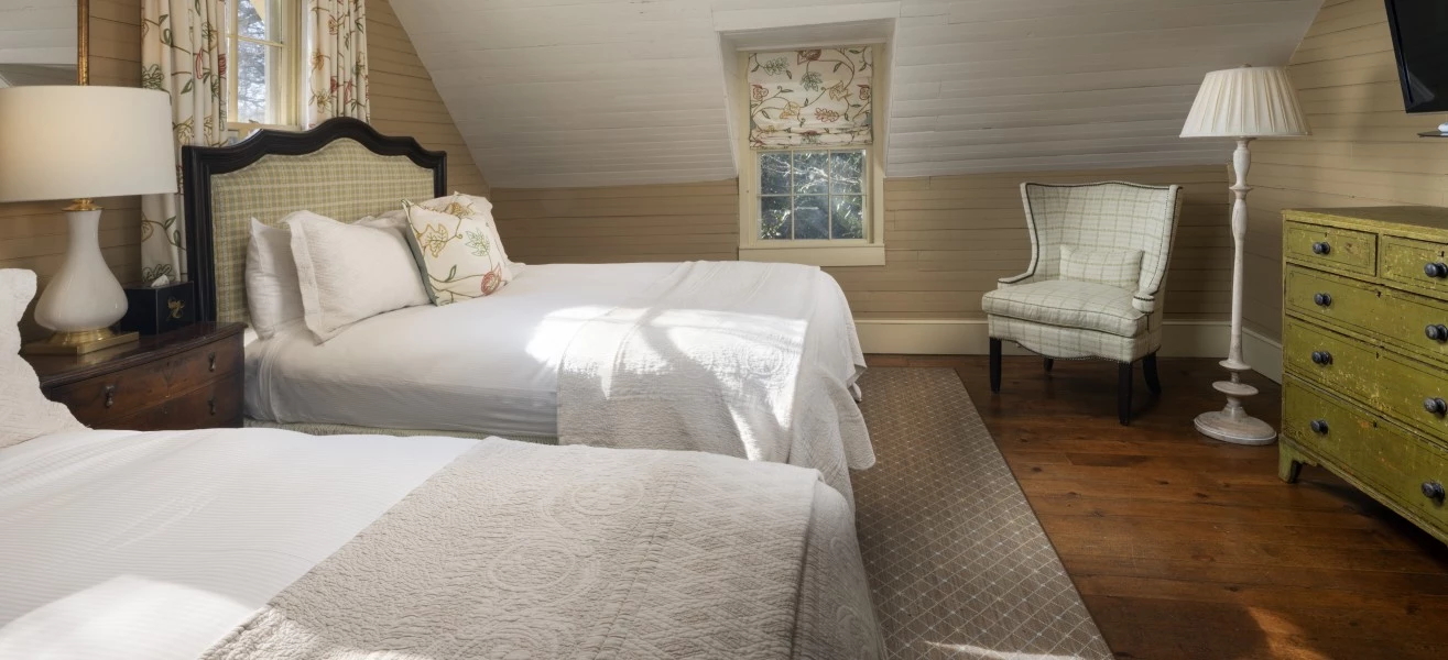 a bedroom with two beds and a chair