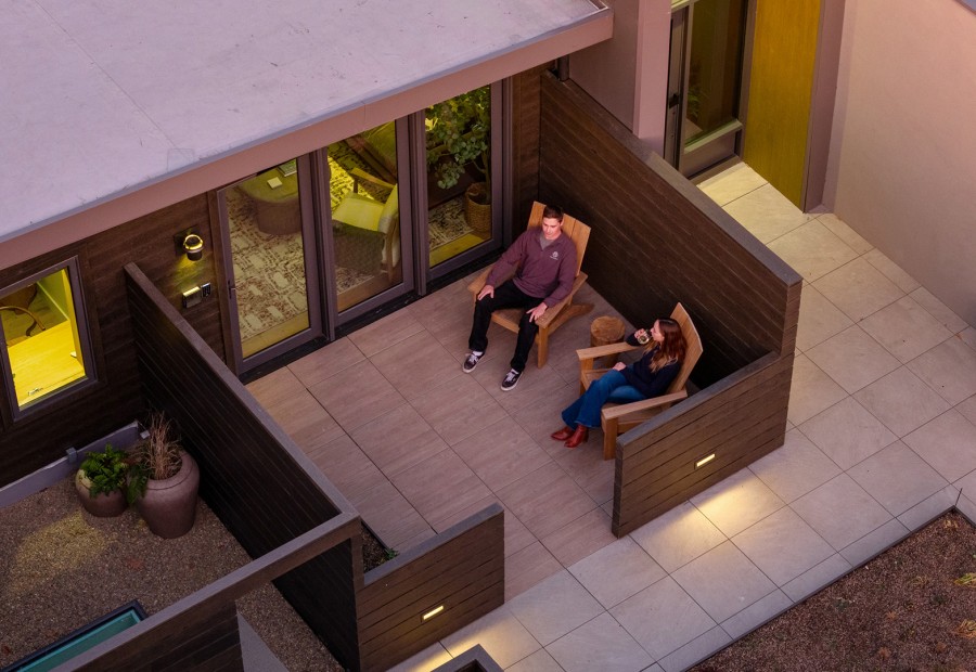 a man and woman sitting on chairs outside of a house