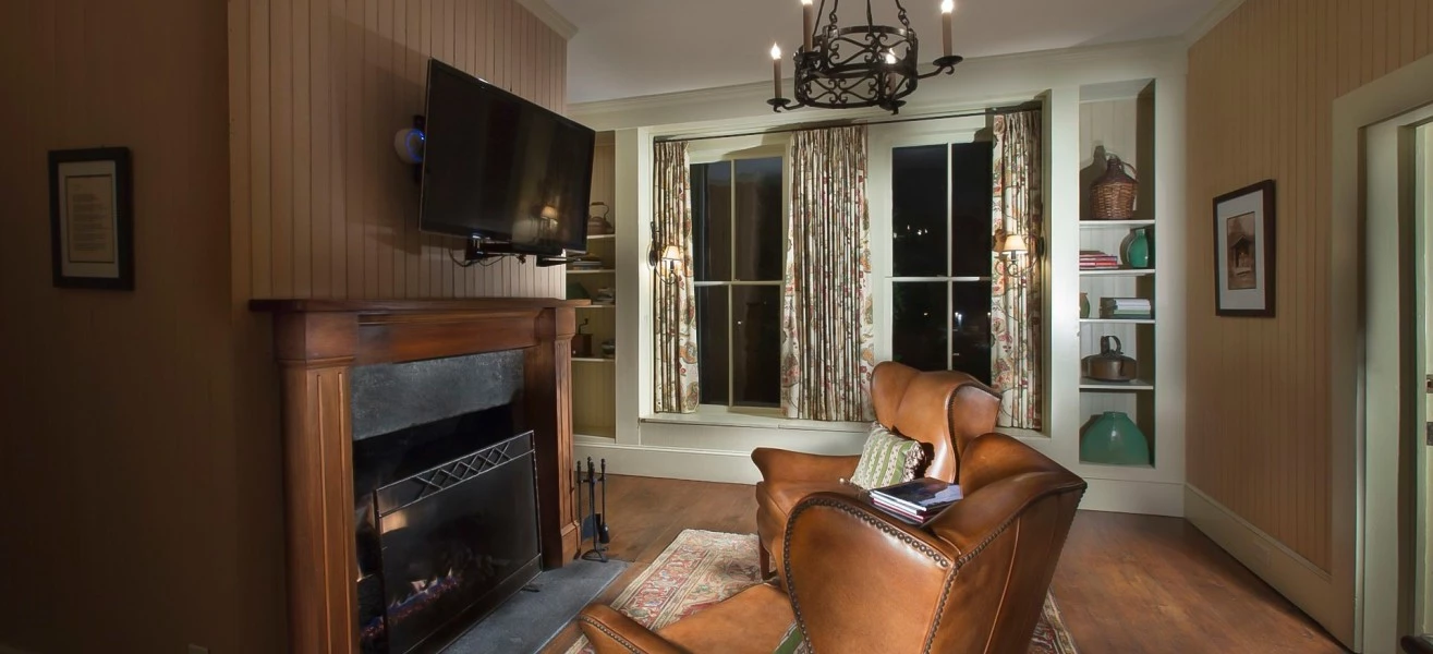 a living room with a fireplace and leather chairs