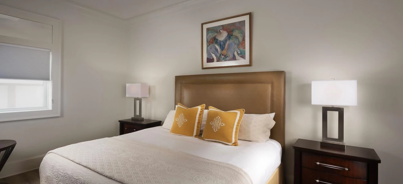 a bed with a brown headboard and a painting above it