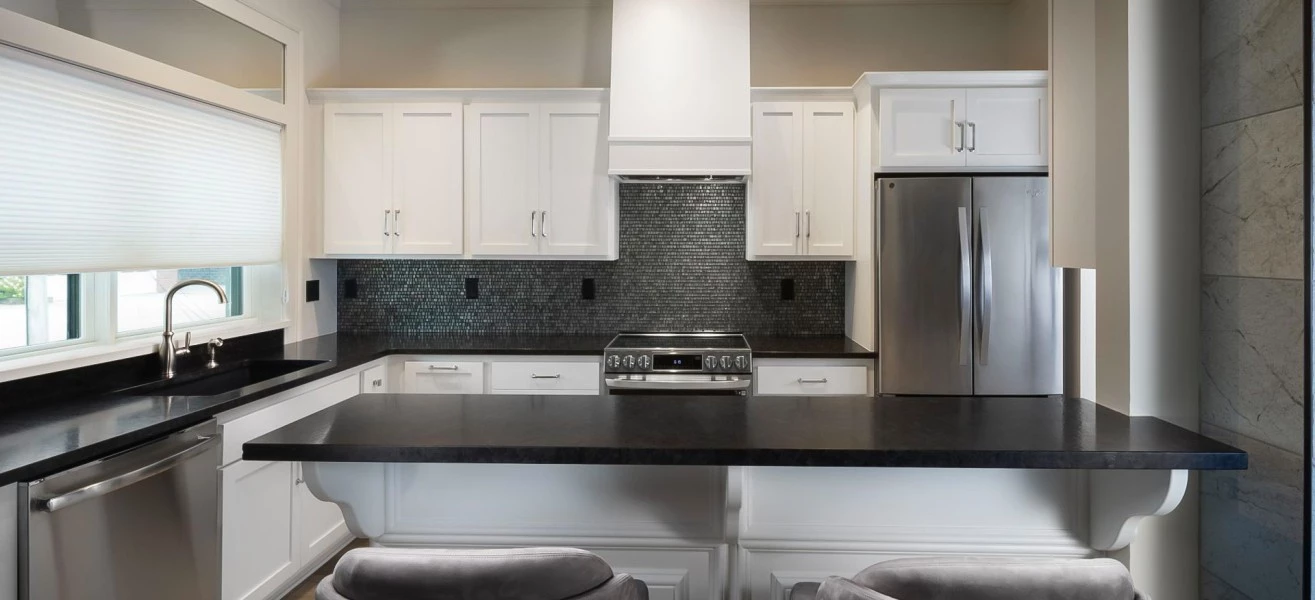 a kitchen with a black countertop and chairs