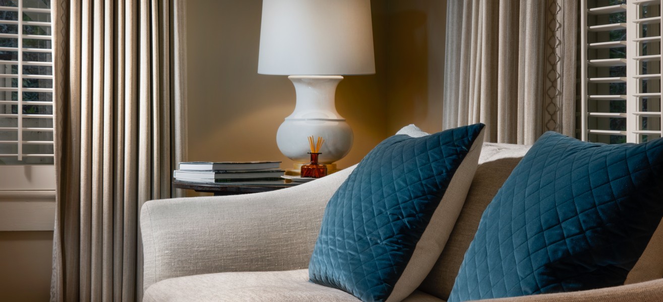a couch with blue pillows and a lamp on a table