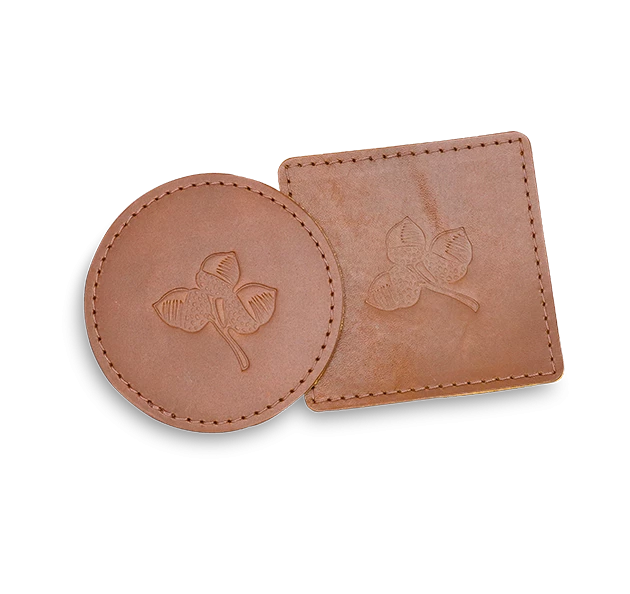 a brown coasters with a leaf engraved on them