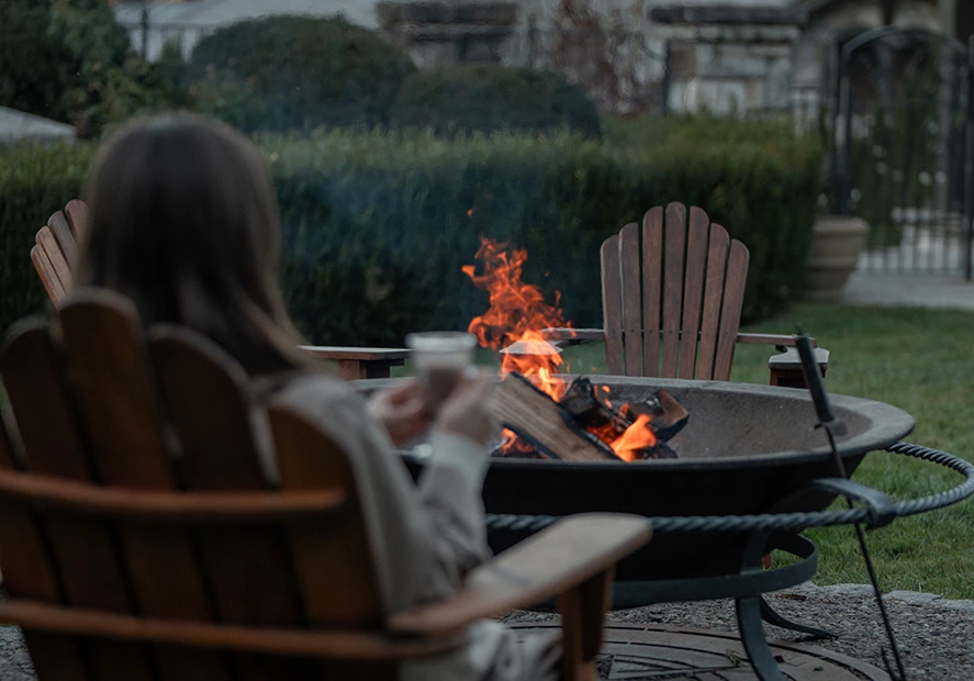a woman sitting in a chair by a fire pit