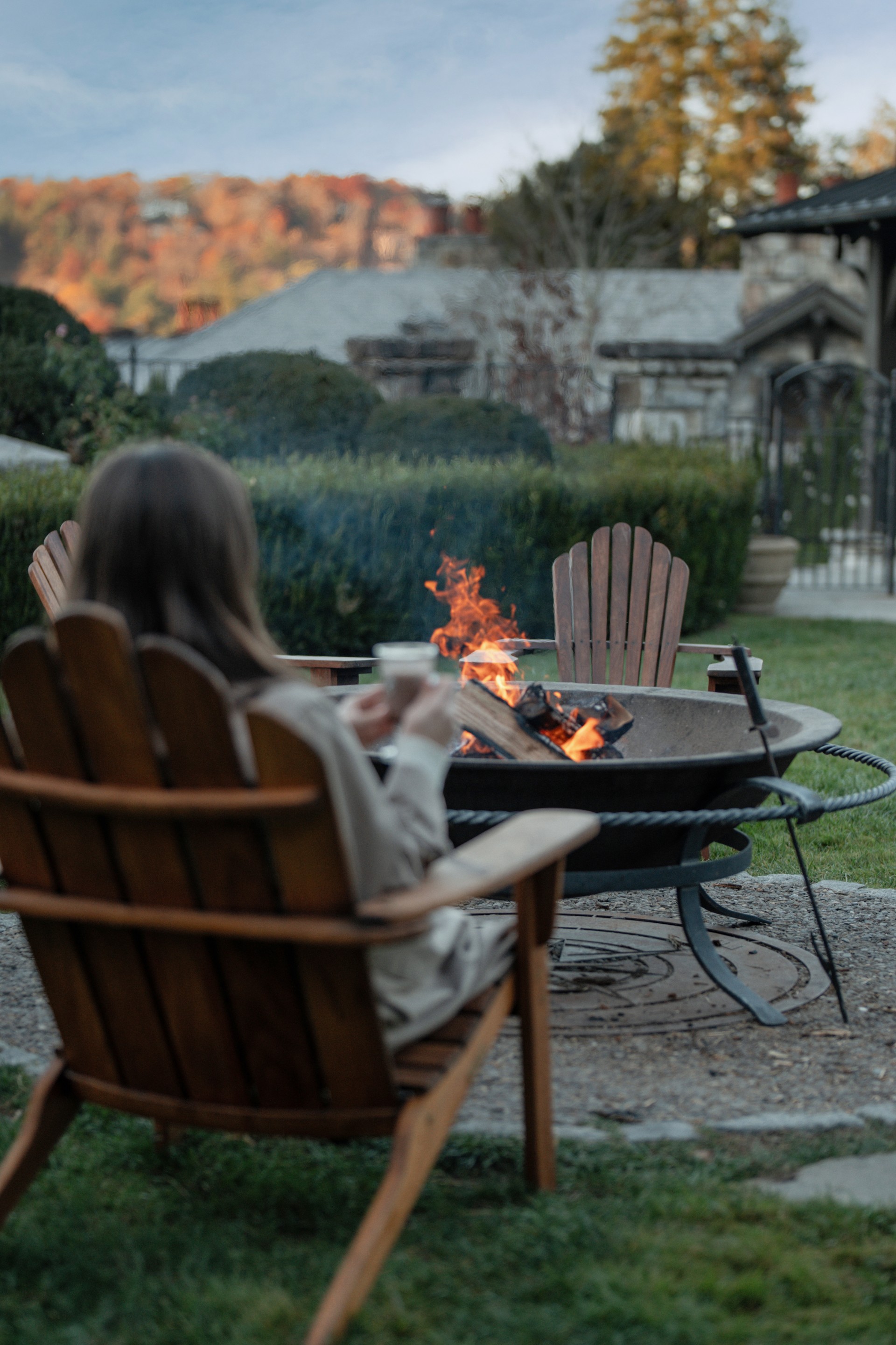 a woman sitting in a chair by a fire pit