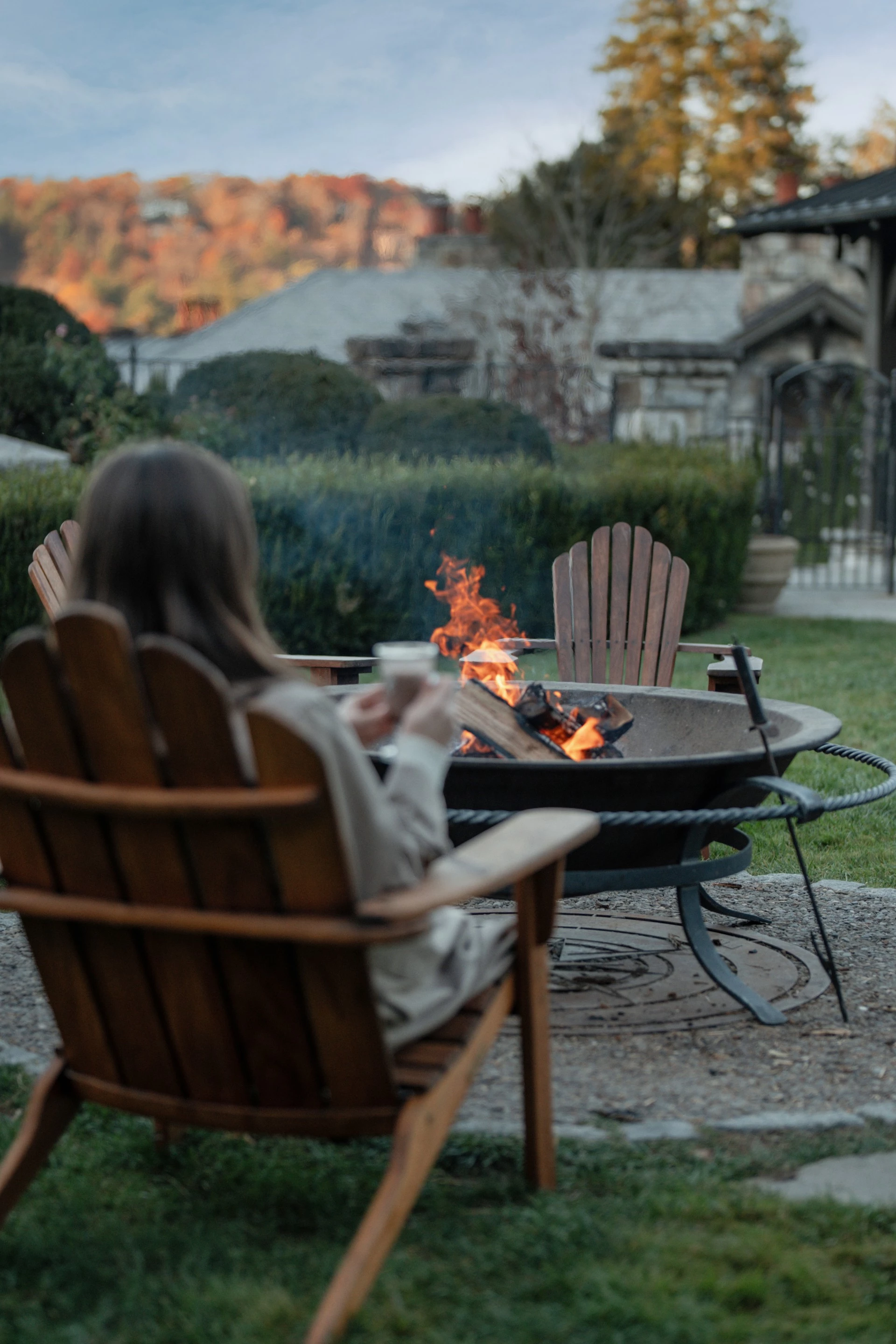 a woman sitting in a chair by a fire pit