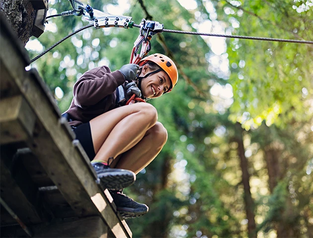 a woman wearing a helmet and harness on a zip line