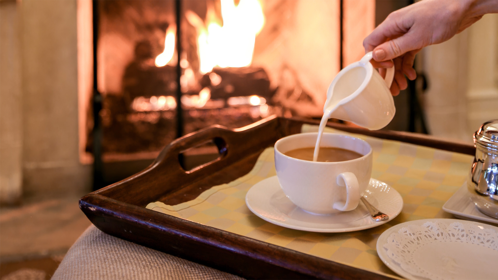 a person pouring milk into a cup of coffee