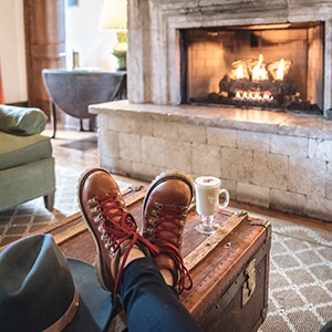 a person's feet on a trunk with a hat and a cup of coffee