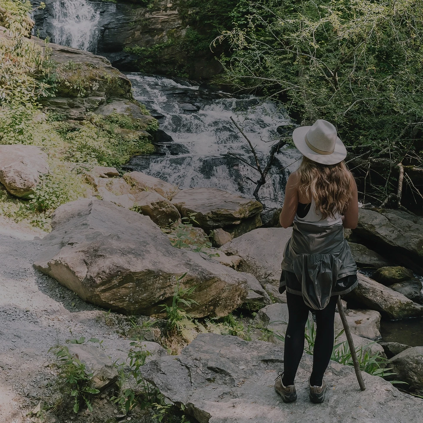 a woman standing on a rock near a river