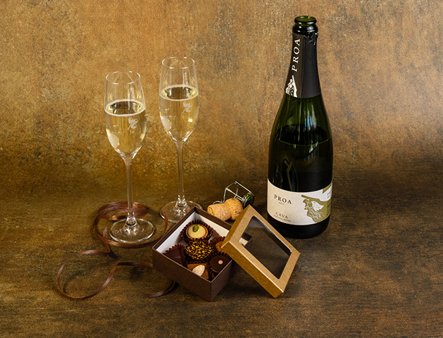 a bottle of champagne next to a box of chocolates