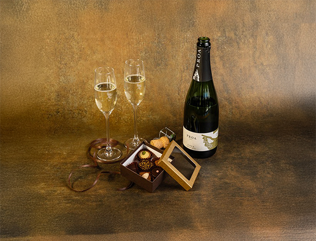 a bottle of champagne next to a box of chocolates
