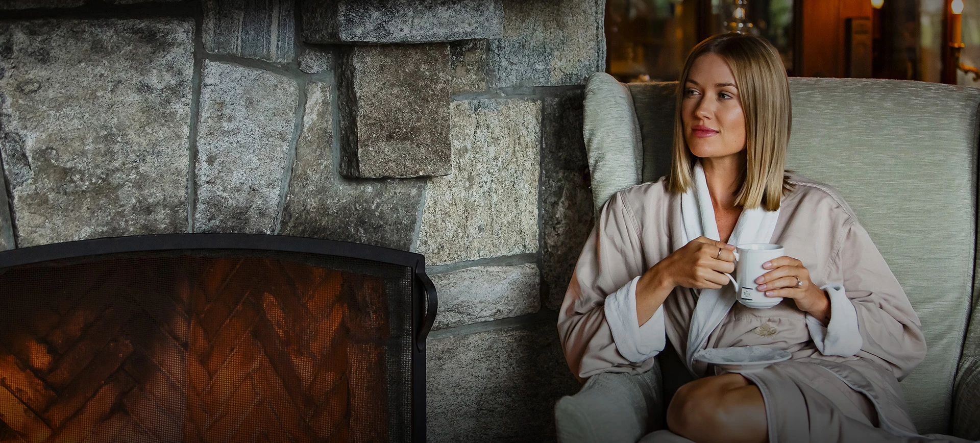 a woman sitting in a chair by a fireplace