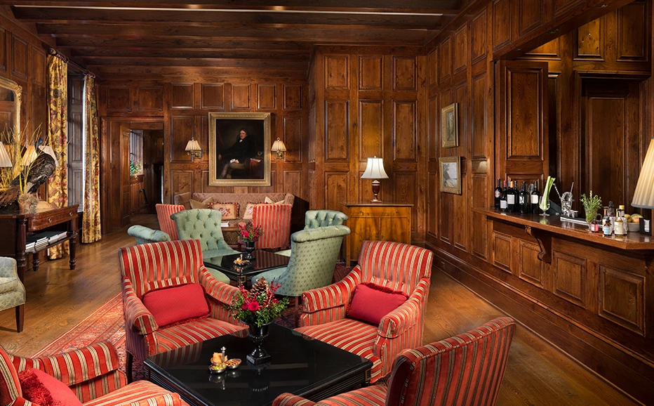 a room with wood paneled walls and a table with chairs and a wine bottle