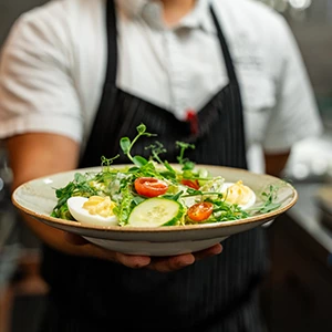 a person holding a plate of salad