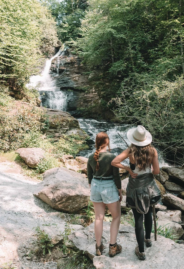two women standing next to a waterfall