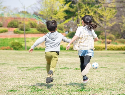 a boy and girl running with a ball