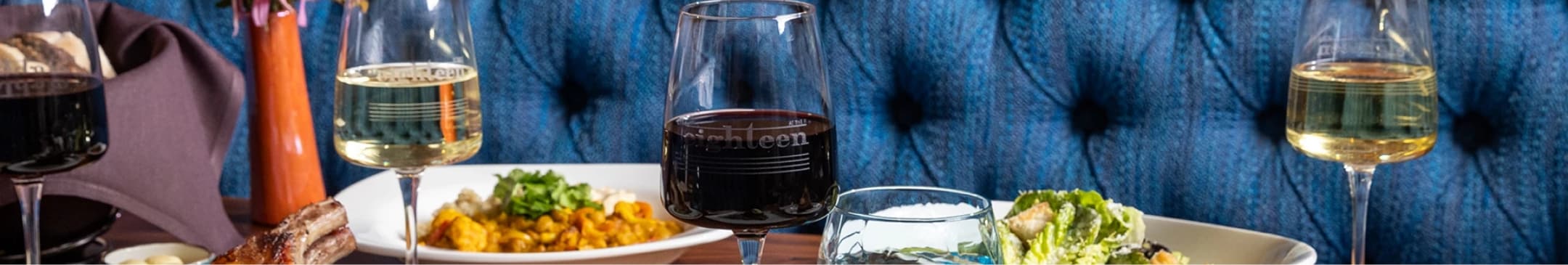 a glass of wine with a plate of food on the table