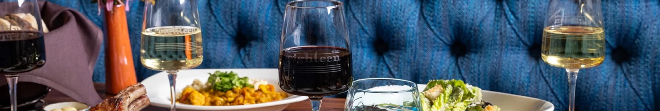 a glass of wine with a plate of food on the table