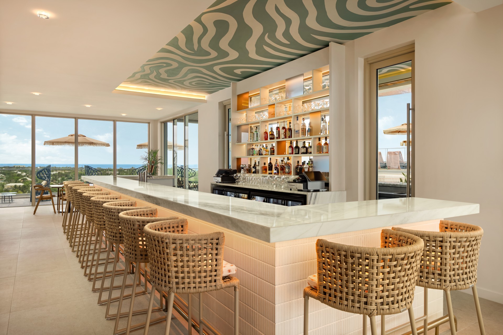 a bar with chairs and a shelf with bottles