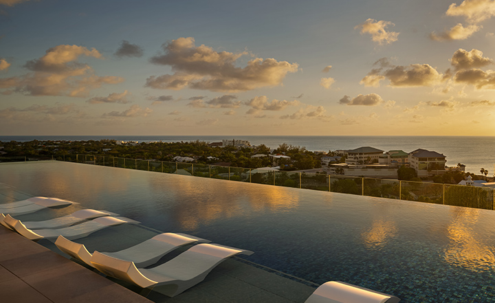 a pool with chairs and a view of the ocean