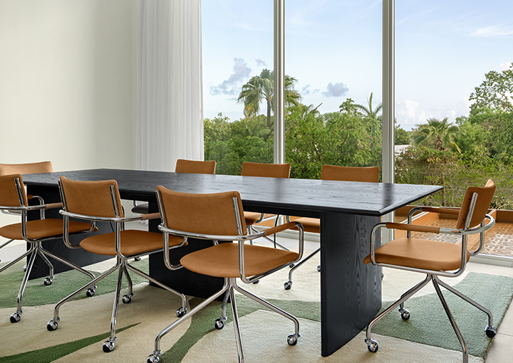 a table with chairs in a room with large windows