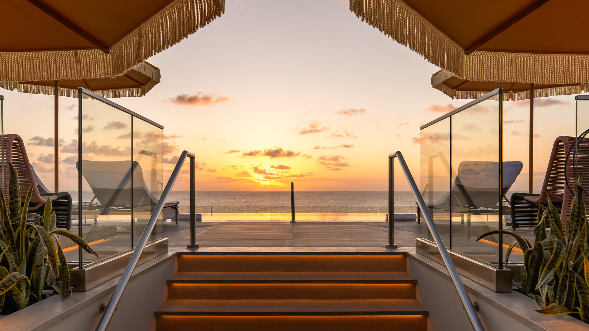 a deck with a view of the ocean and a sunset