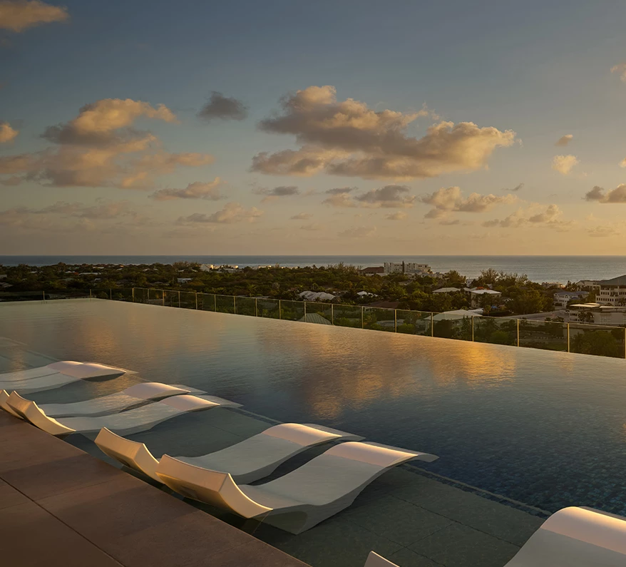 a pool with lounge chairs and a view of the ocean
